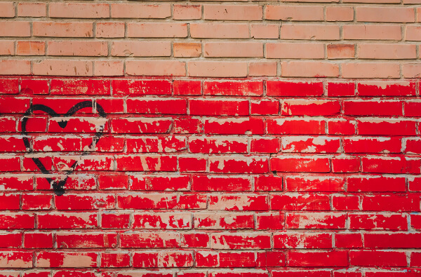 Black heart drawn on red brick wall by Ashkan Forouzani on Unsplash